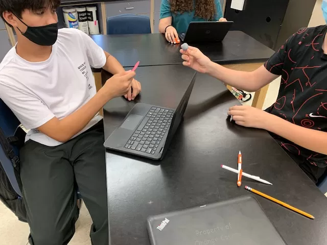 students holding 3D printed objects while on a laptop