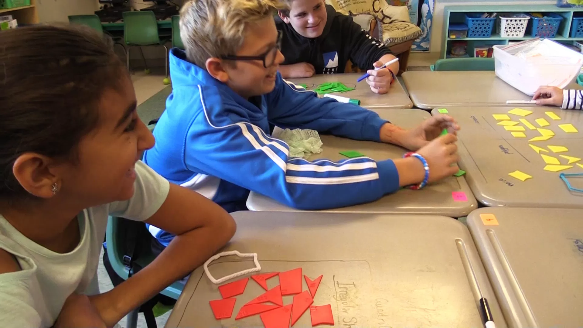 Students sitting at a table and laughing grouping shapes