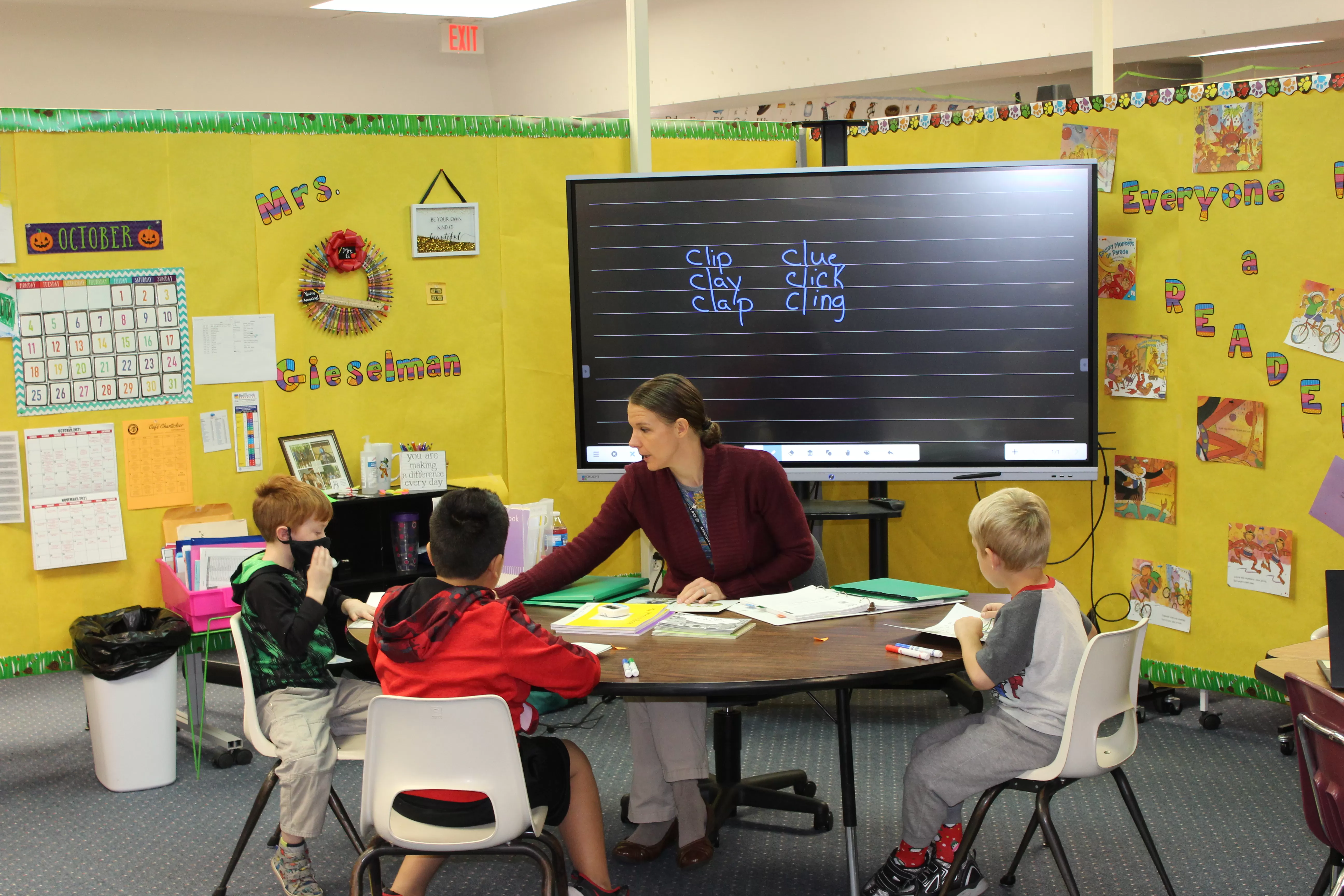 students round a table talking to the teacher with a Boxlight ProColor in the background