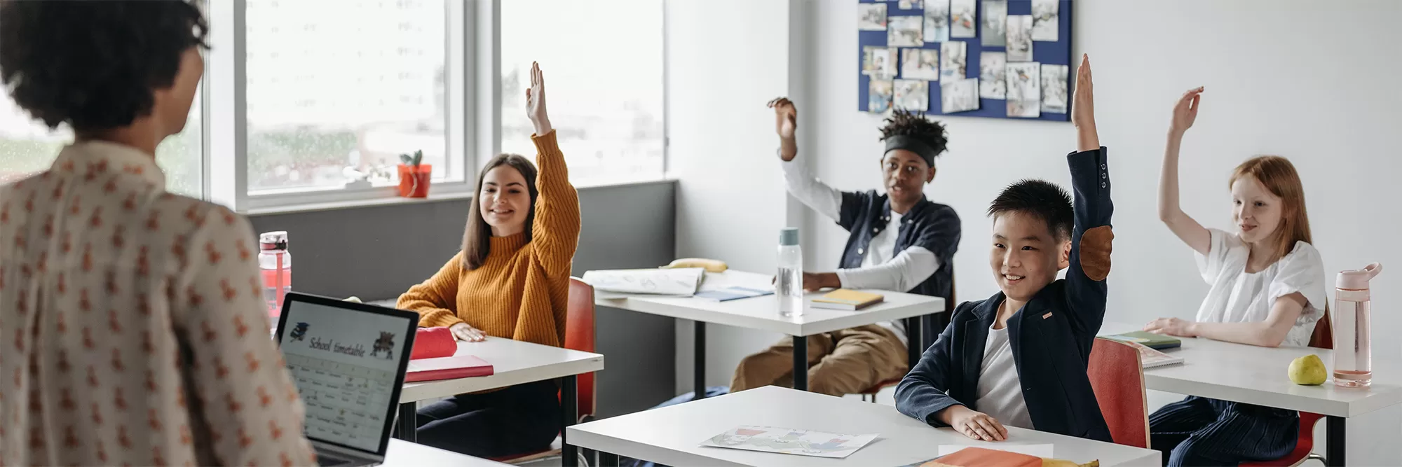 class of four people raising their hands