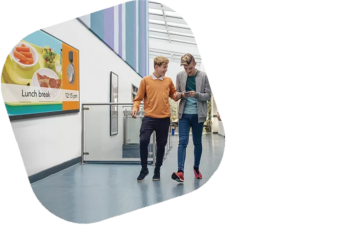 Students walking through a hall with digital signage. image in a square at an angle