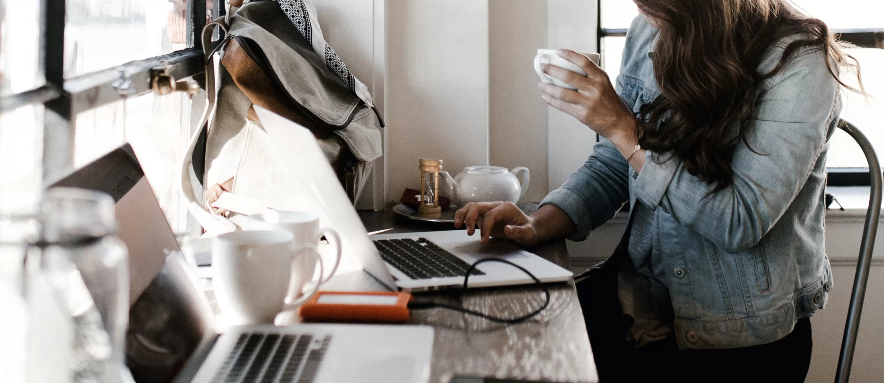 person using a laptop and drinking a tea
