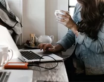 person using a laptop and drinking a tea