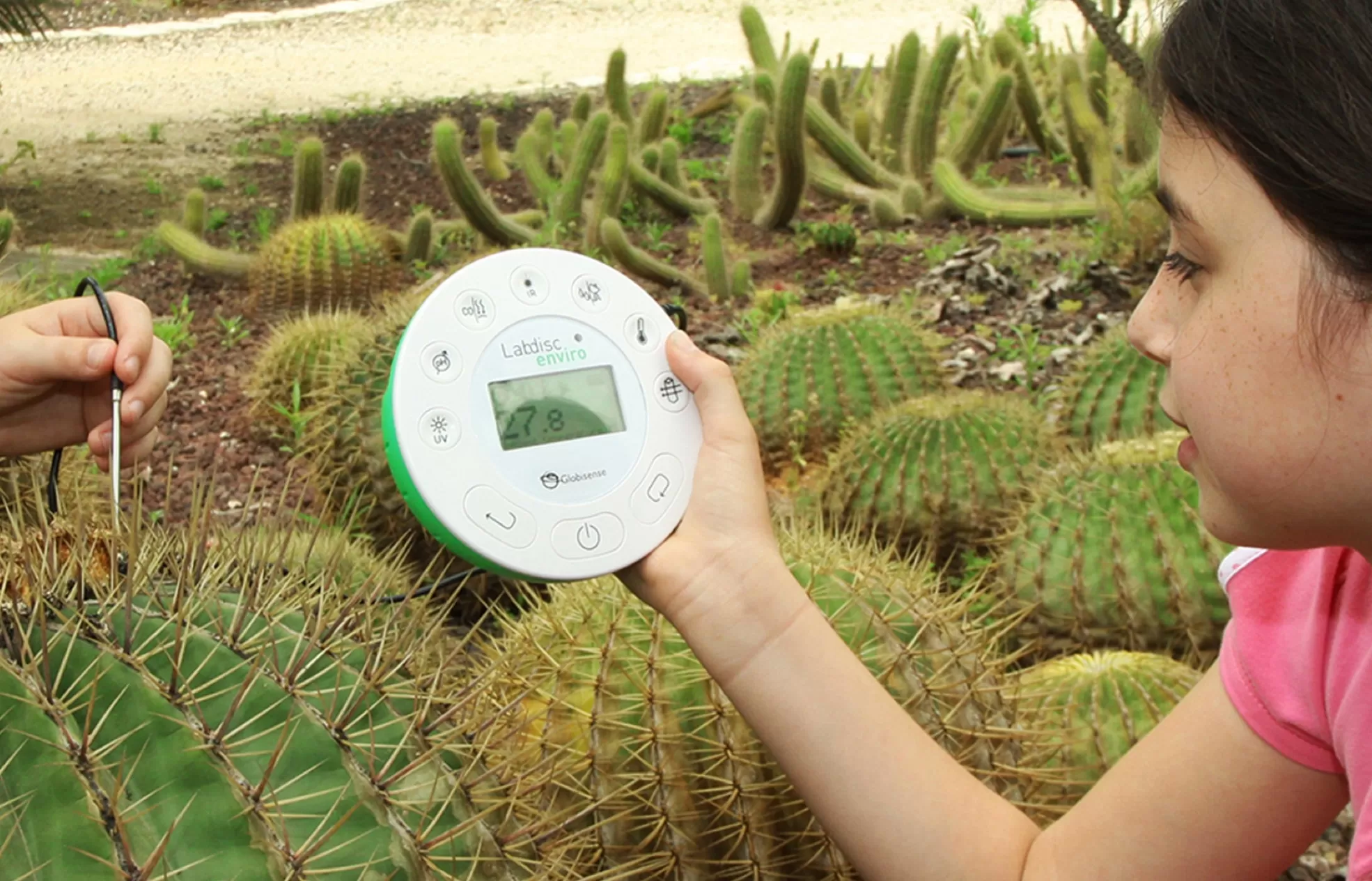 student holding a lab disc in a cactus garden