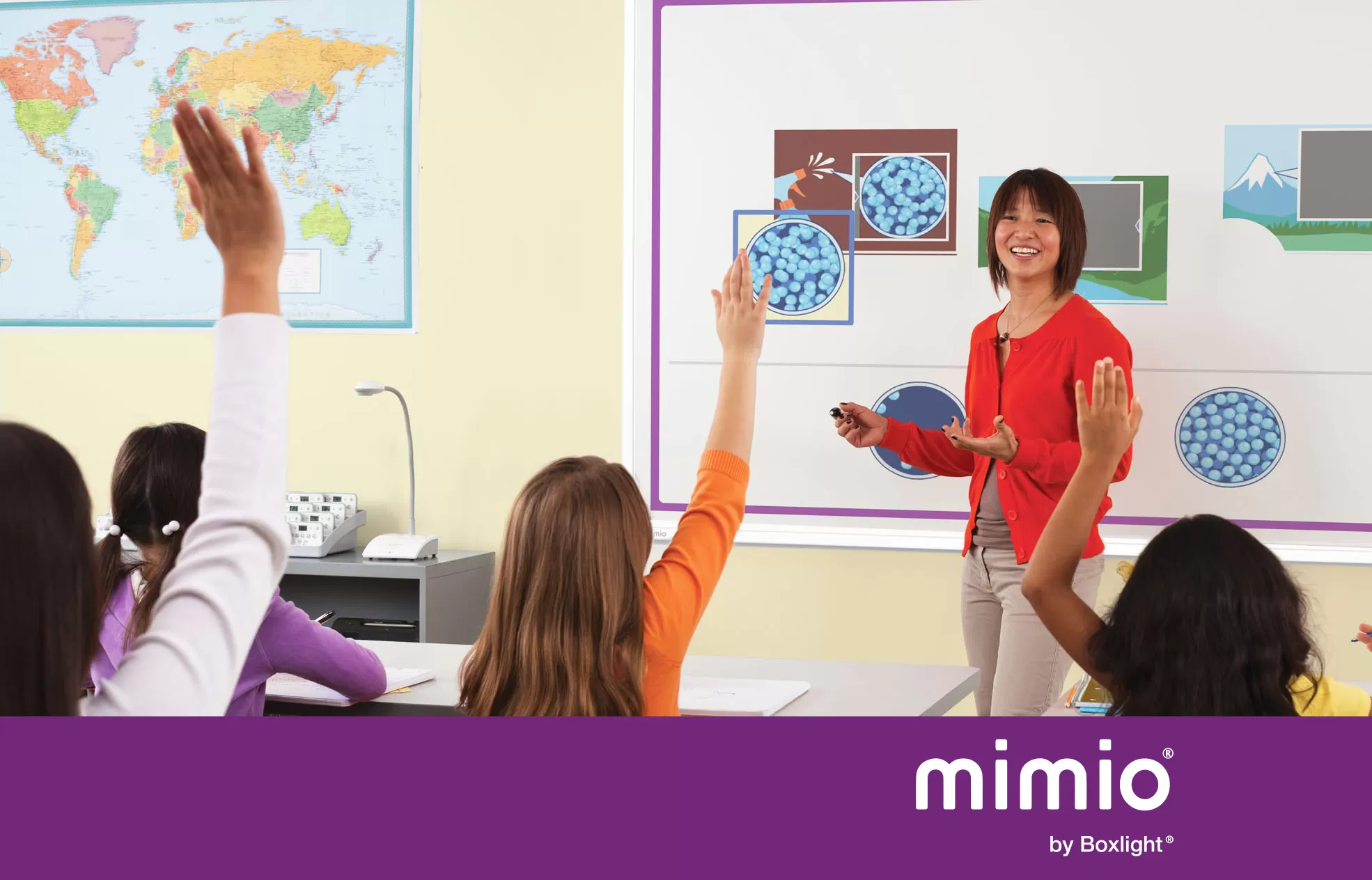 Teacher using MimioBoard in front of class with purple banner saying 'mimio by boxlight' at the bottom