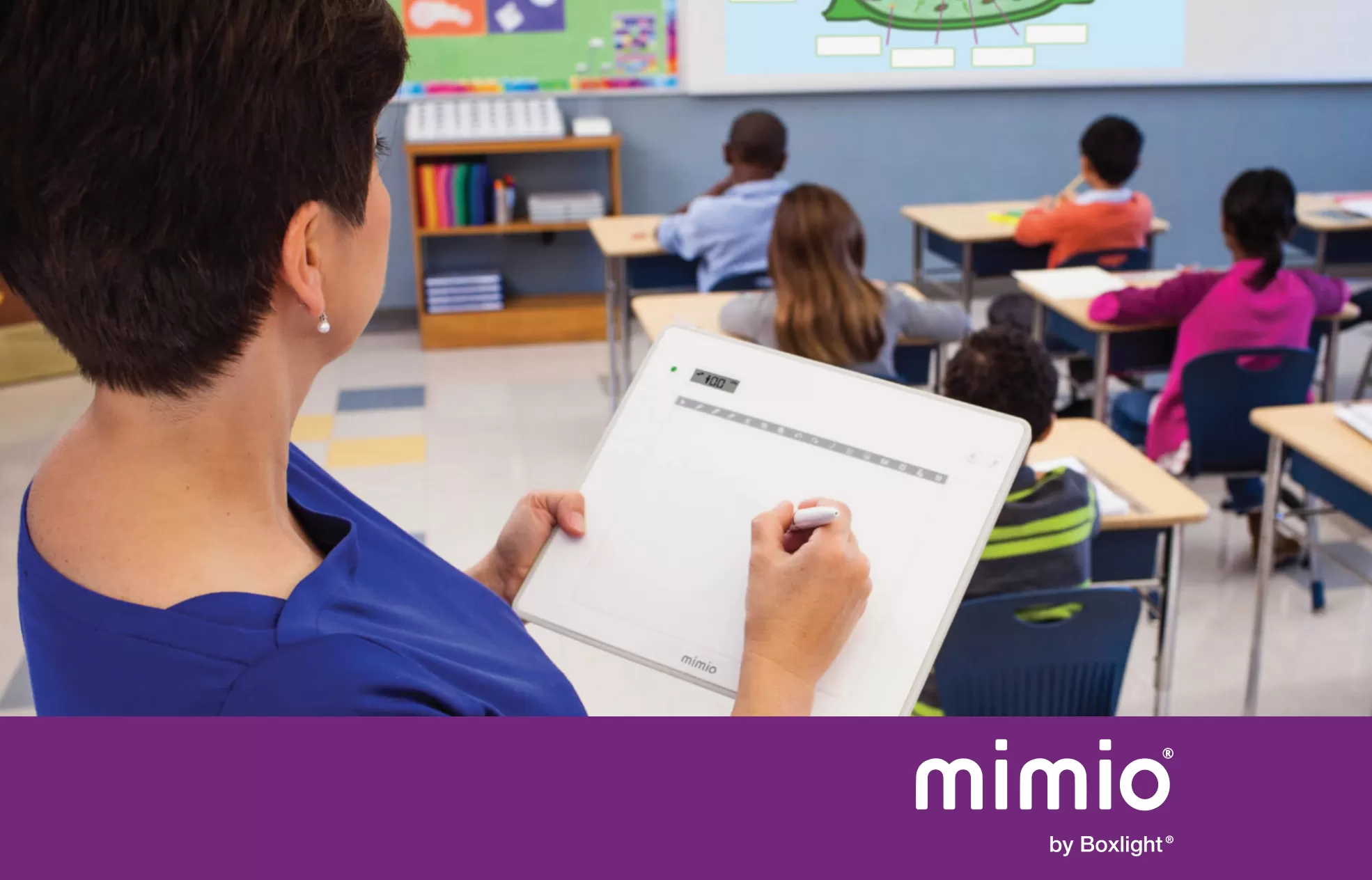 Teacher using MimioPad Wireless Pen Tablet in a classroom to write on the whiteboard. Purple banner saying 'mimio by boxlight' across the bottom